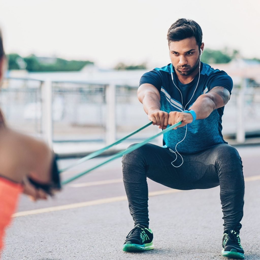 An image showing a man training with a resistance band as part of his resistance training.