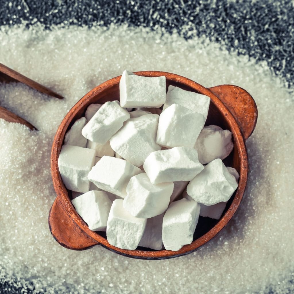 Refined sugar cubes on a wooden scoop.