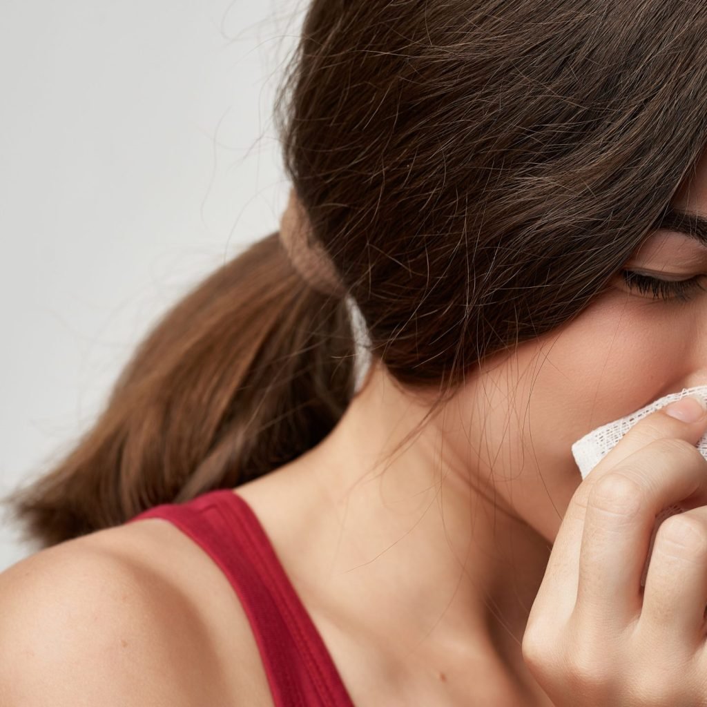 A young woman suffering from the symptoms of common cold.
