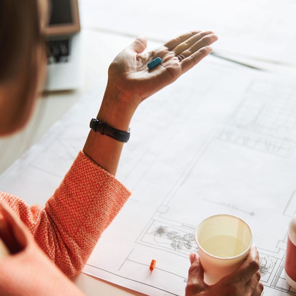 A woman in the middle of her work is seen taking a supplement to increase her Vitamin D Levels.
